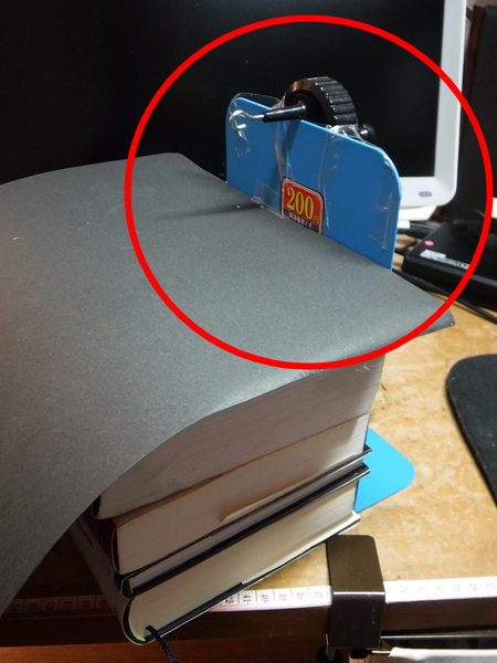 ゴムワインダーをブックエンドの背面にテープで固定したところ。厚い本を数冊載せて、重しにしている。